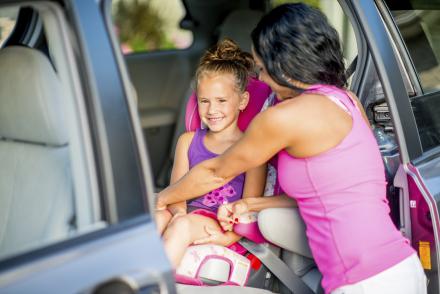 Mom buckling in child in car seat