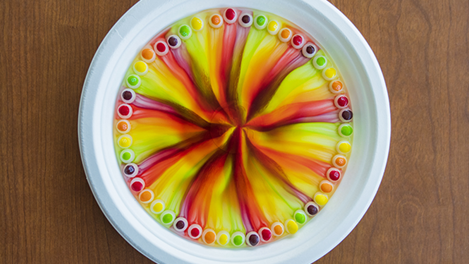 Plate with a skittles around the edges with rainbow created after adding hot water
