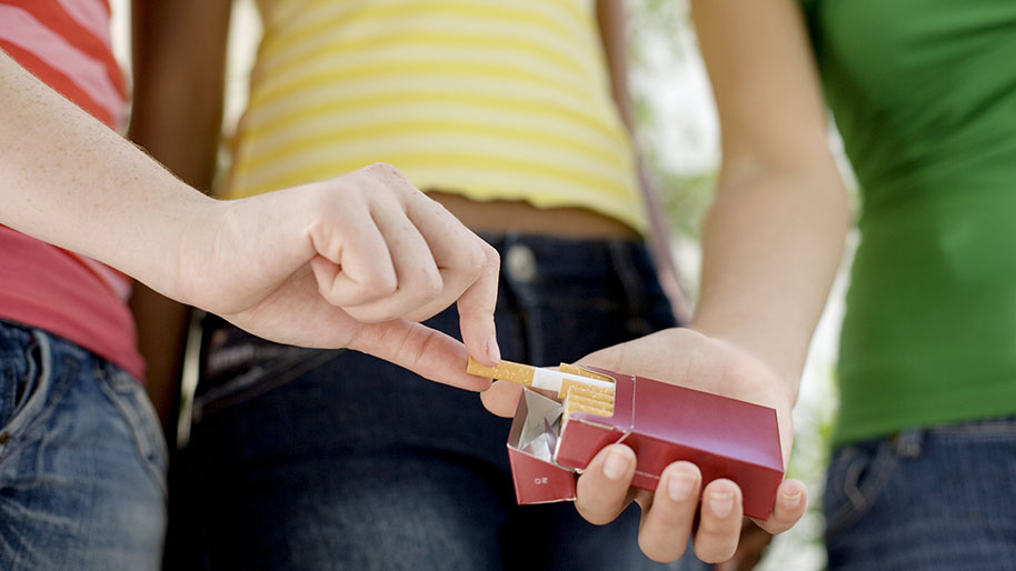 Group of teens removing a cigarettes from a package