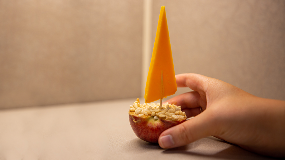 Apple topped with peanut butter and rice krispies with a cheese "flag"