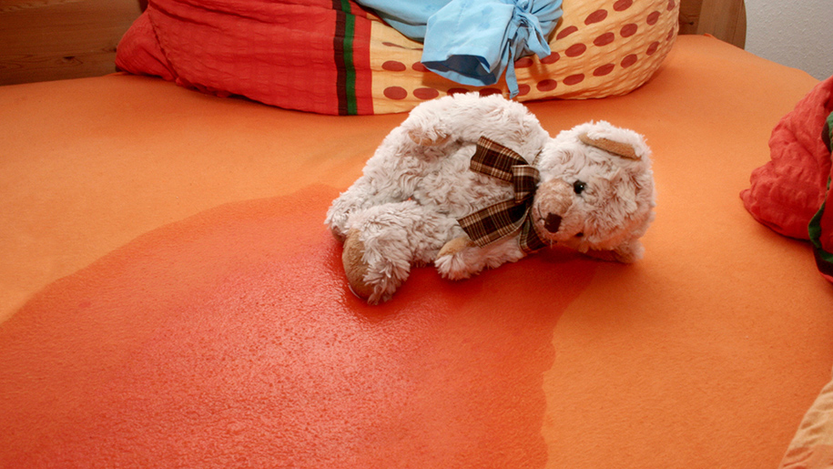 Teddy bear laying on a wet sheet