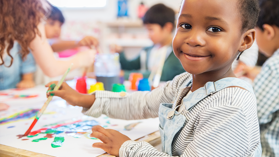 Child painting in a classroom setting