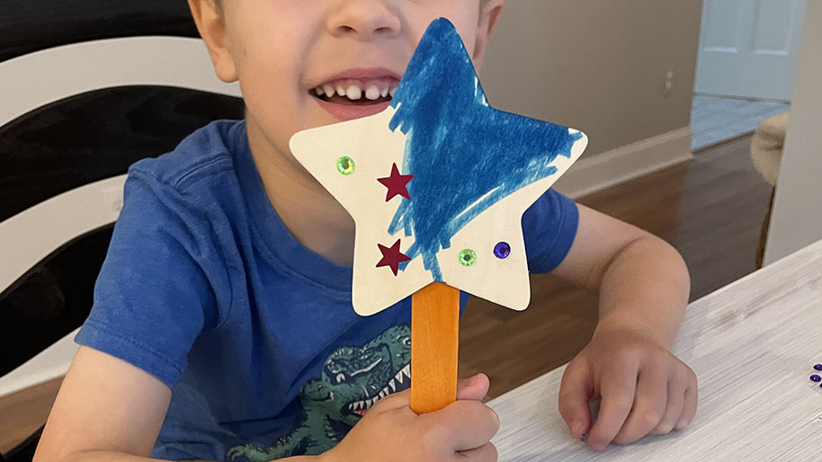 Child holding star wand attached to stick colored and stickers