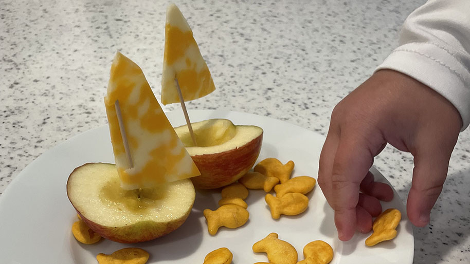 Apples with cheese sails and child fishy crackers on plate