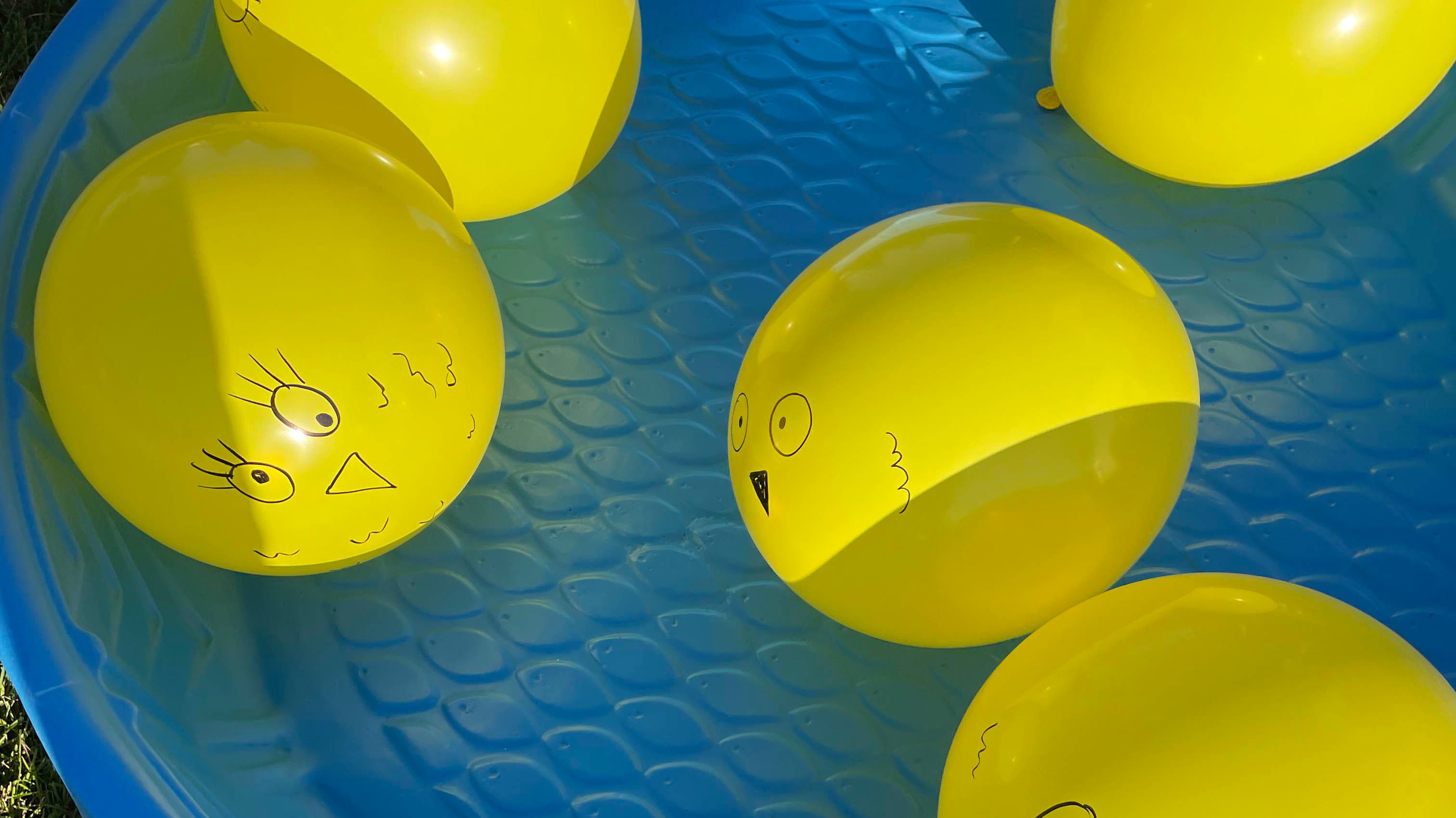 Yellow balloons with face drawings place in blue pool