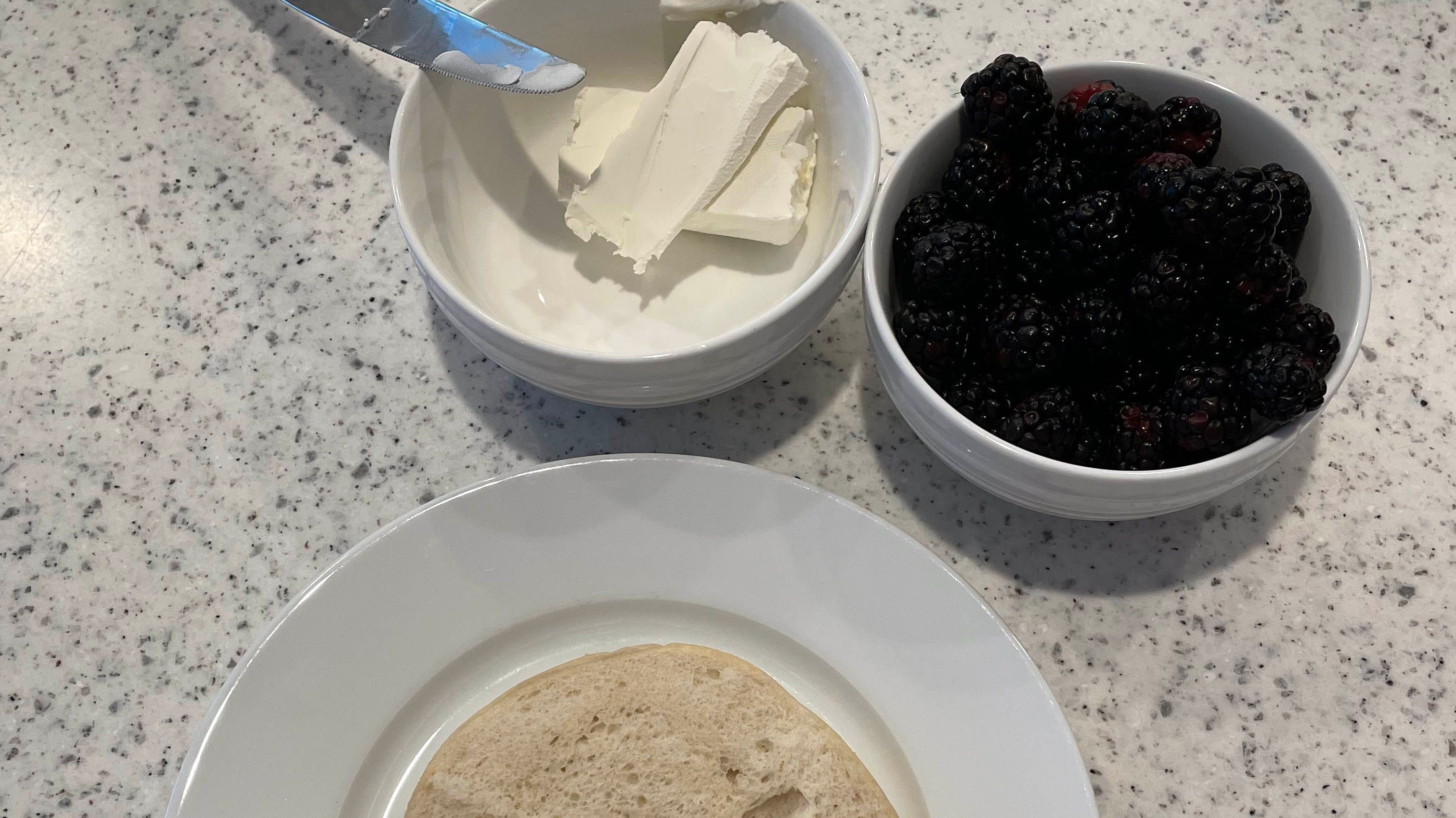 Cream cheese, plastic knife, raspberries and bagel 