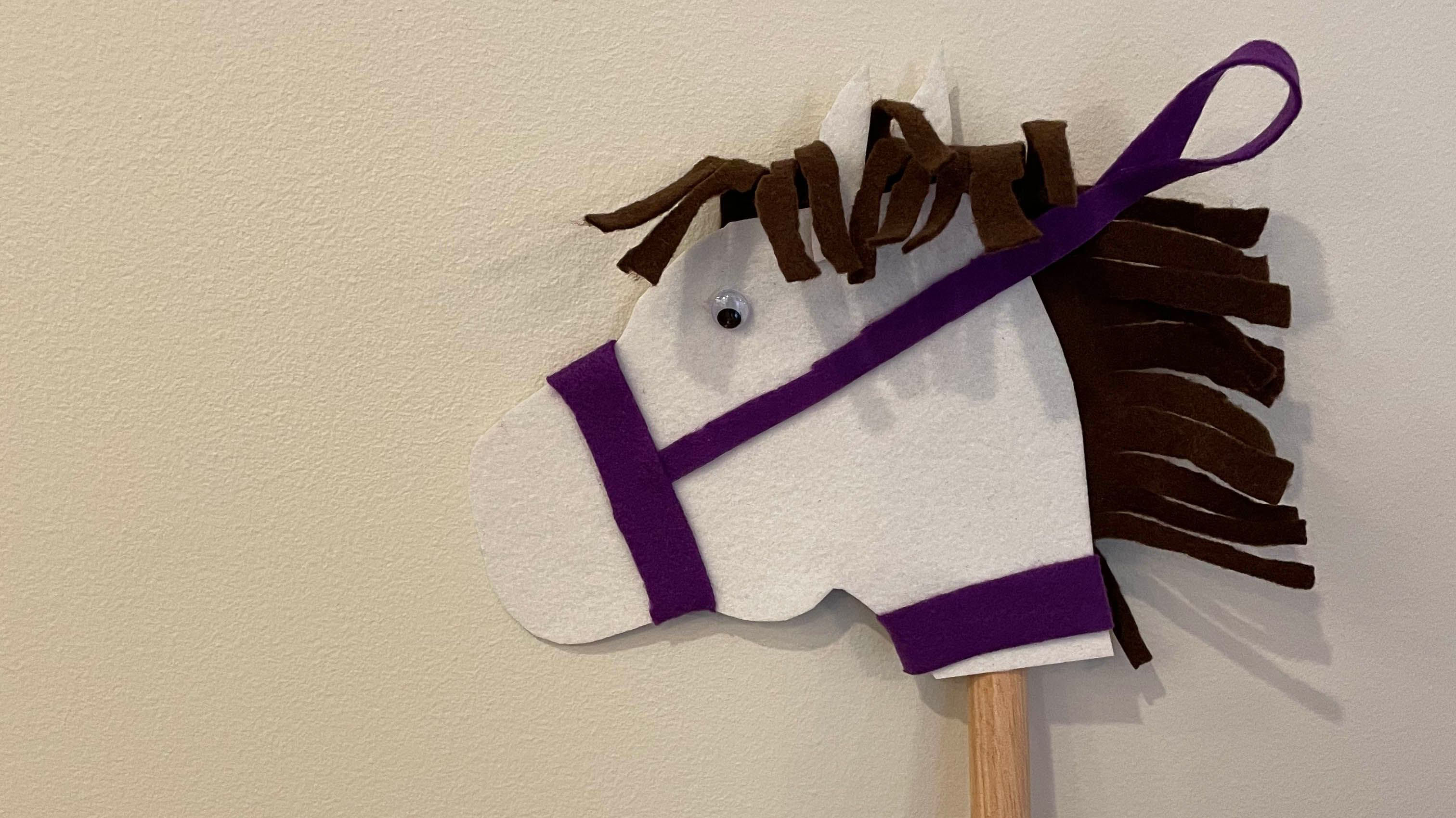 White, purple and black felt pieces shaped as a horse attached to stick