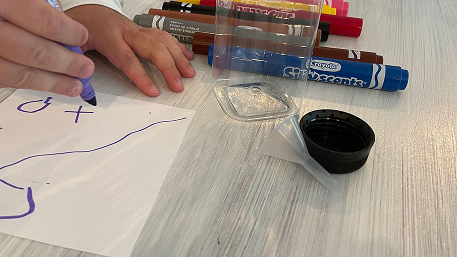 Child writing message on paper with markers to put in bottle