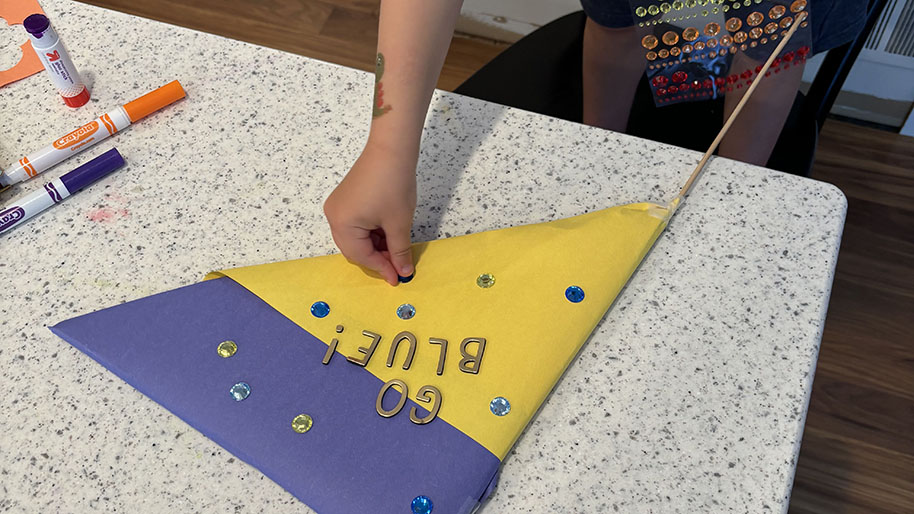 Child decorating pennant/foam board triangle using the coloring supplies and decorations..