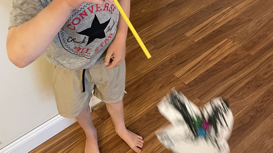 Child blowing through straw to make superhero fly