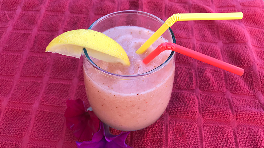Glass of strawberry lemonade slushee with a straw
