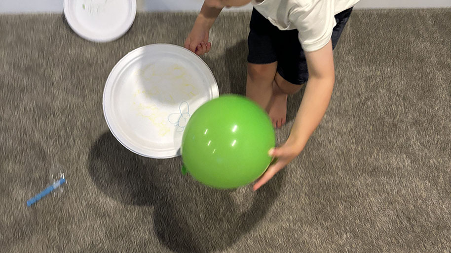 Child scooping balloon on to paper plate