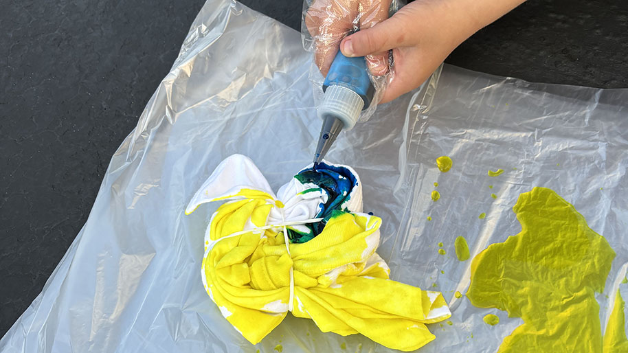 Child squeezing colors onto the shirt in a preferred pattern/areas.