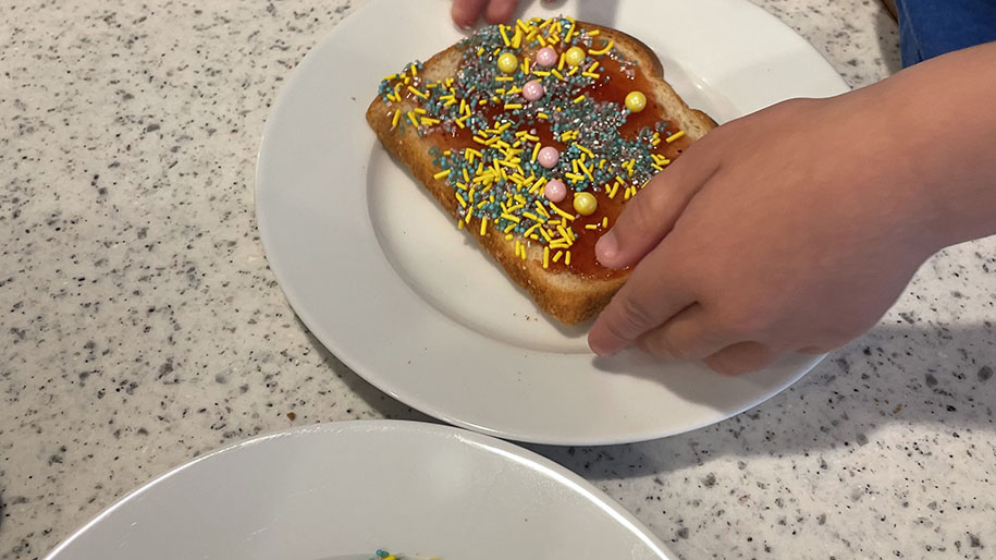 Child holding toast with sprinkles and jelly