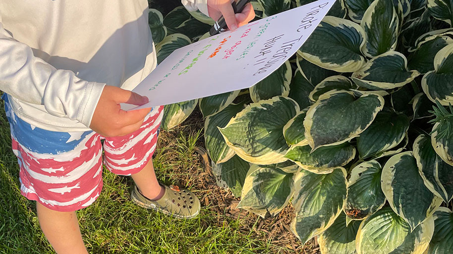 Child walking holding paper with treasure hunt wording