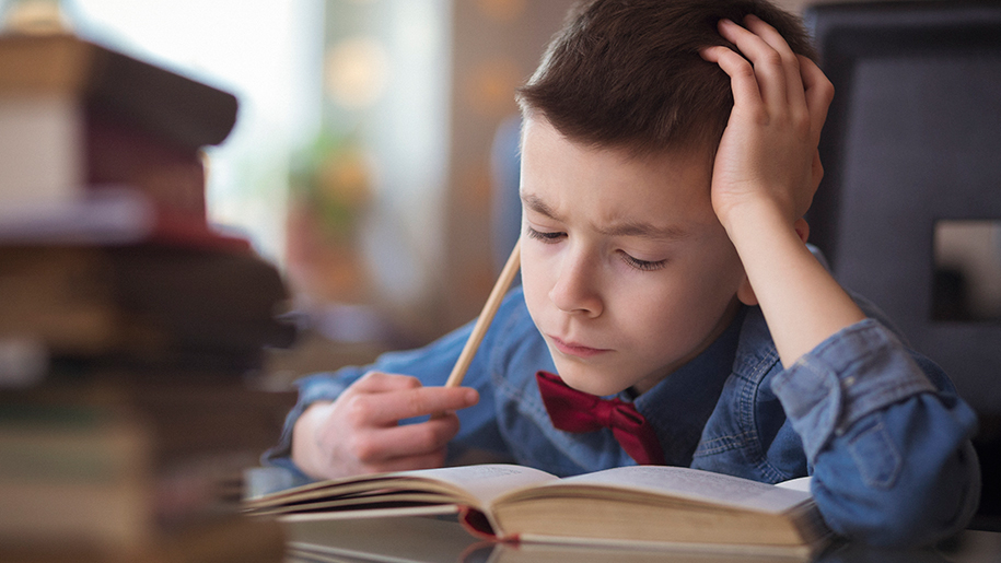 Boy looking troubled as he reads a book