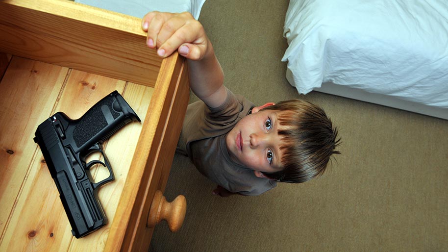Little boy reaching into a drawer for a gun
