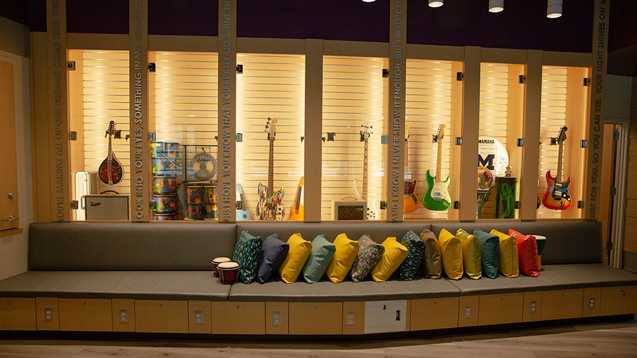 Wrap around bench with pillows with musical insturments displayed in a case behind the bench.