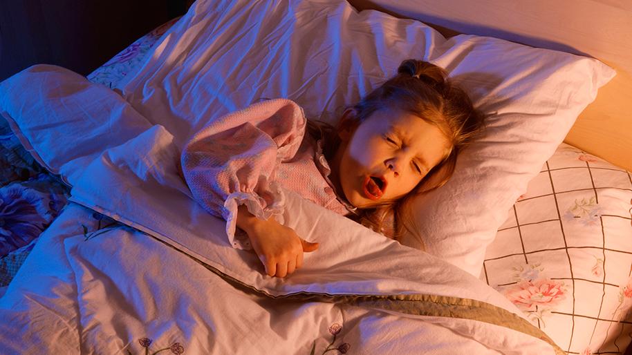 Little girl lying in bed and coughing
