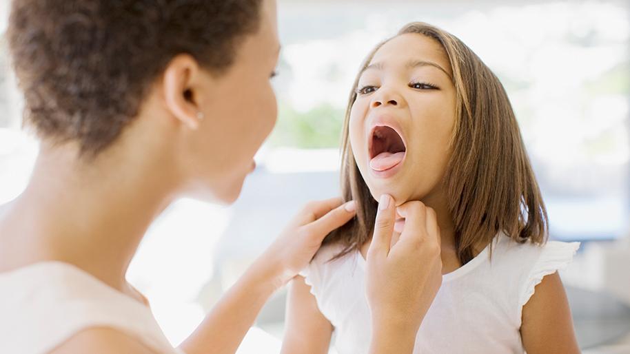 Mother examining a young girl's throat
