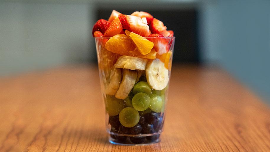 Cup with layered blueberries, grapes, bananas, oranges, & strawberries