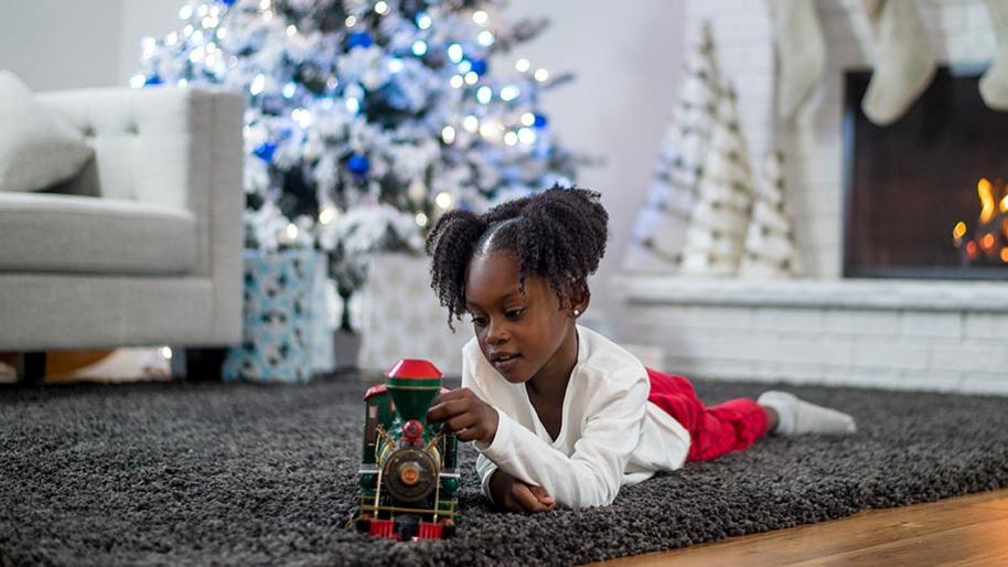 Little girls playing with a train in front of a Christmas tree