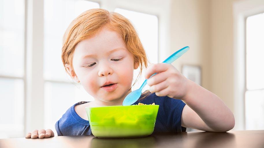 Child eating from a green bowl