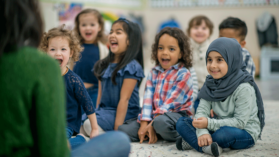 Class of preschoolers sitting in front of a teacher