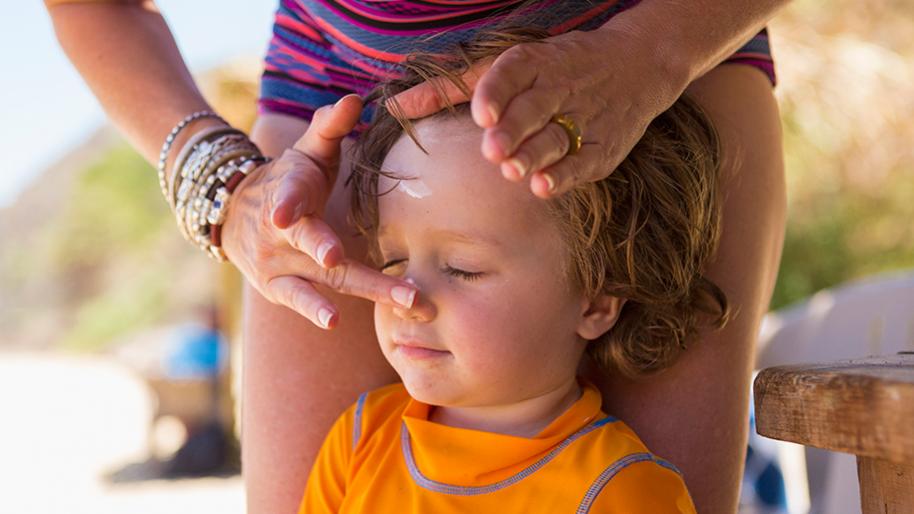 Woman rubbing sunscreen on a childs nose
