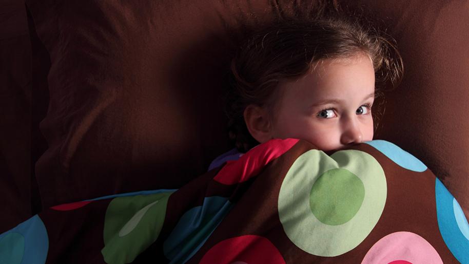 Little girl peeking out from under the covers