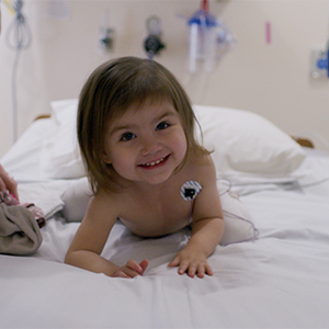 Kid laying in a hospital bed smiling